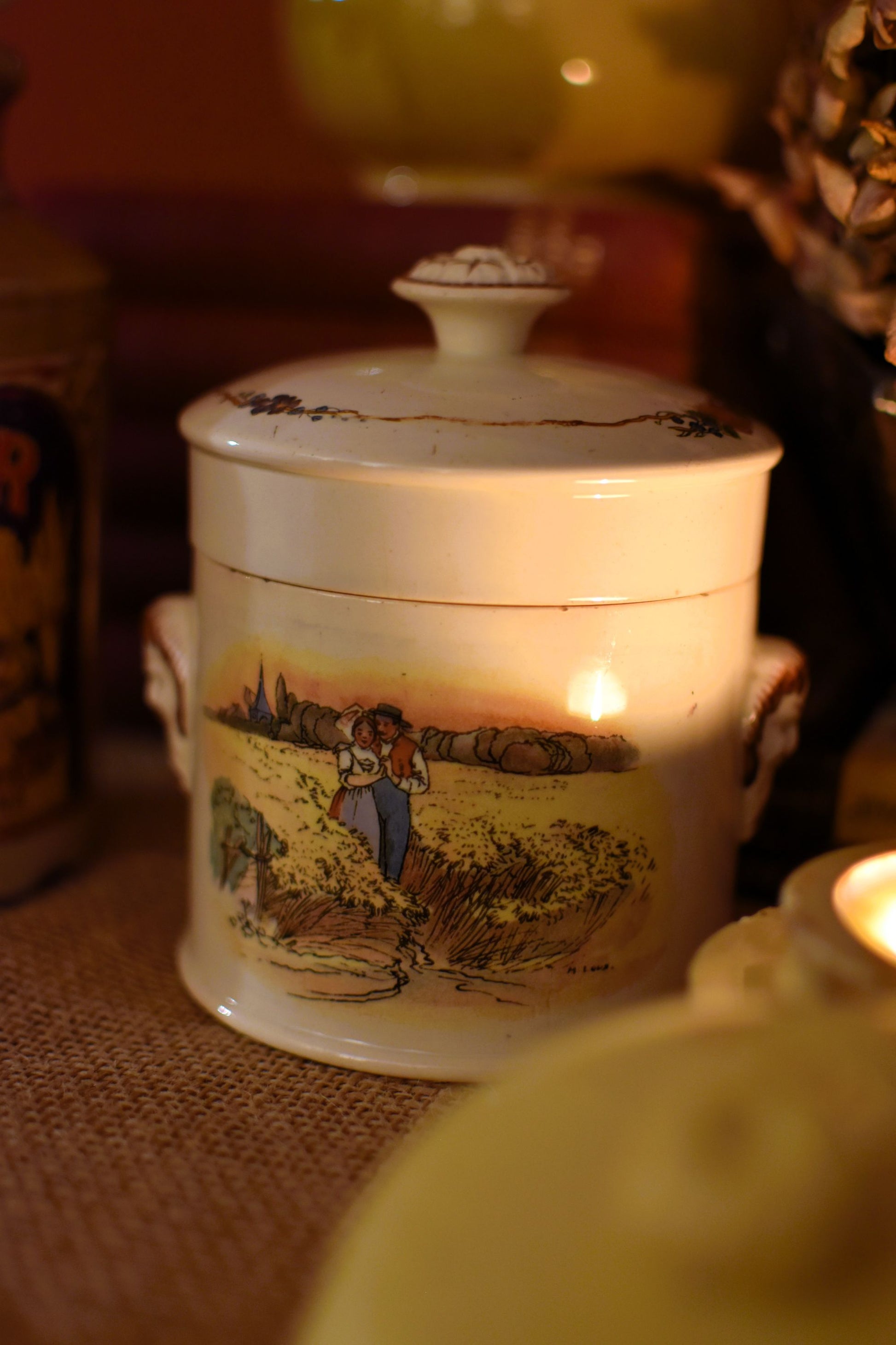 Ceramic jar with lid featuring a scenic design on a textured surface.