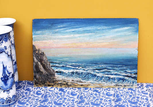 Painting of a coastal scene with waves and cliffs on a yellow wall.