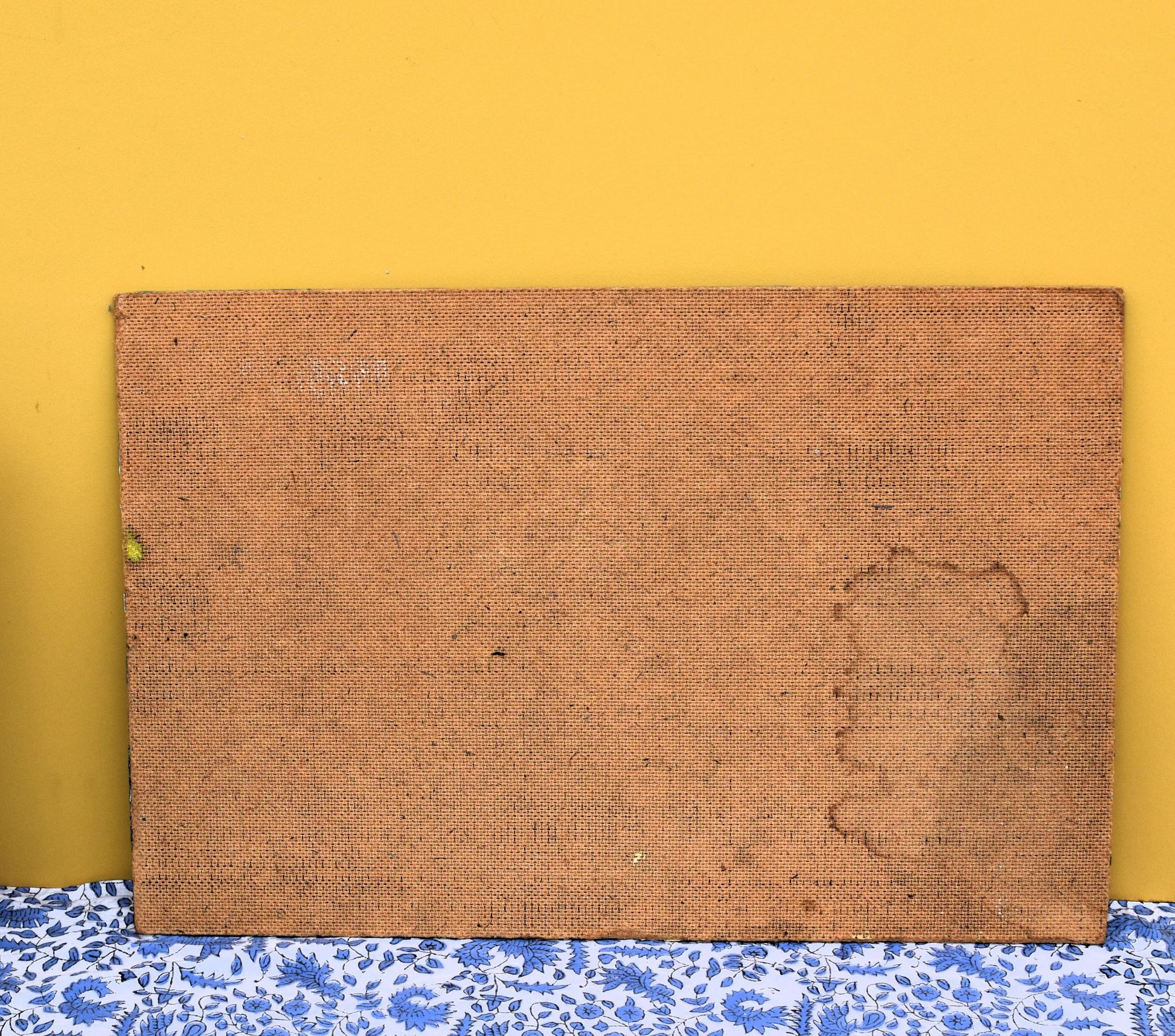 Brown textured board on a yellow wall with a blue floral-patterned baseboard.