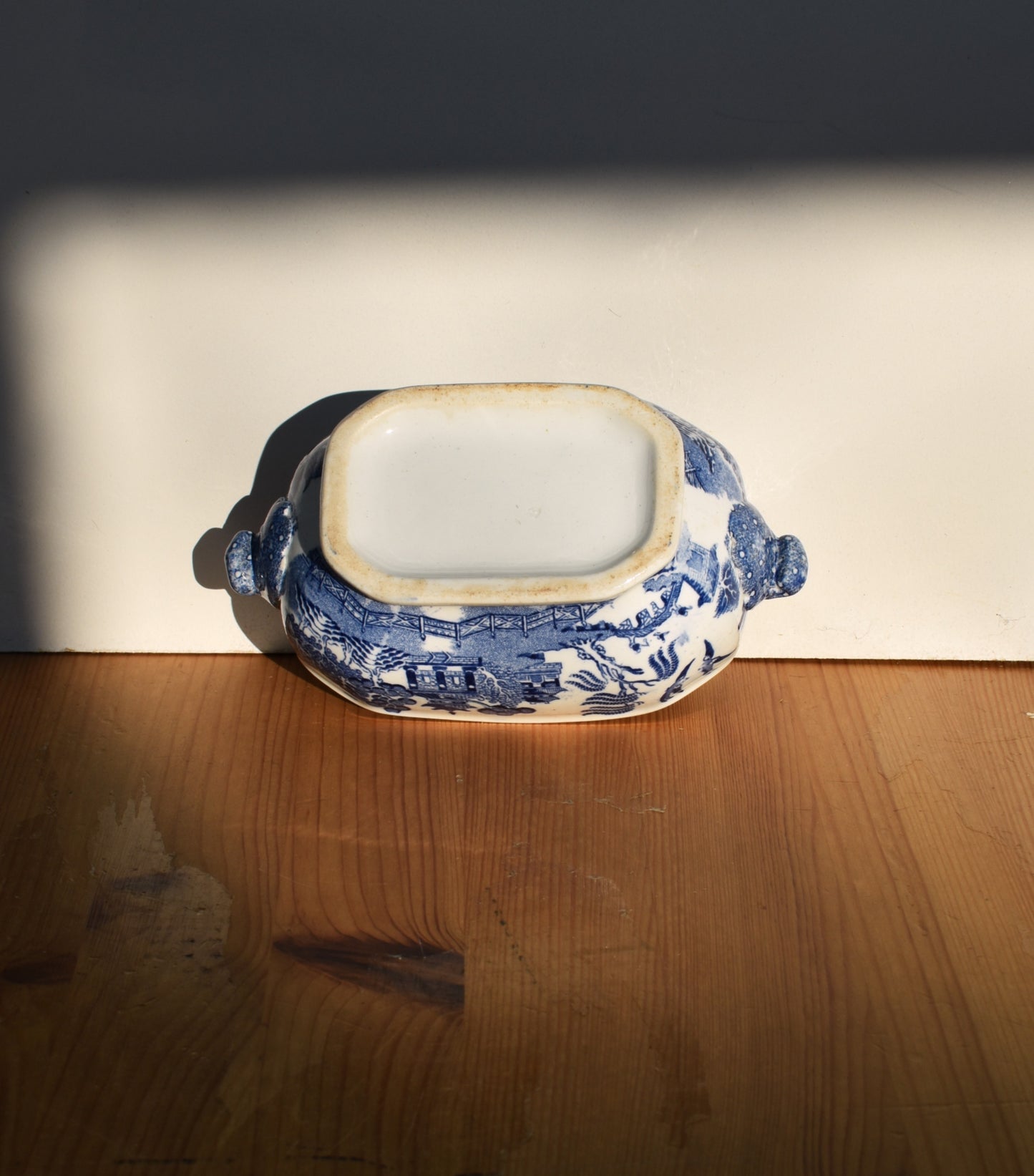 Blue and white ceramic dish on a wooden surface with a dark background