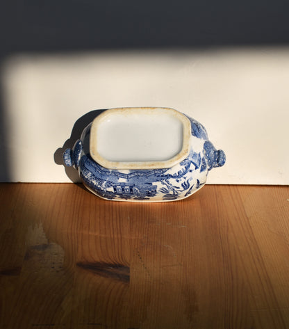 Blue and white ceramic dish on a wooden surface with a dark background
