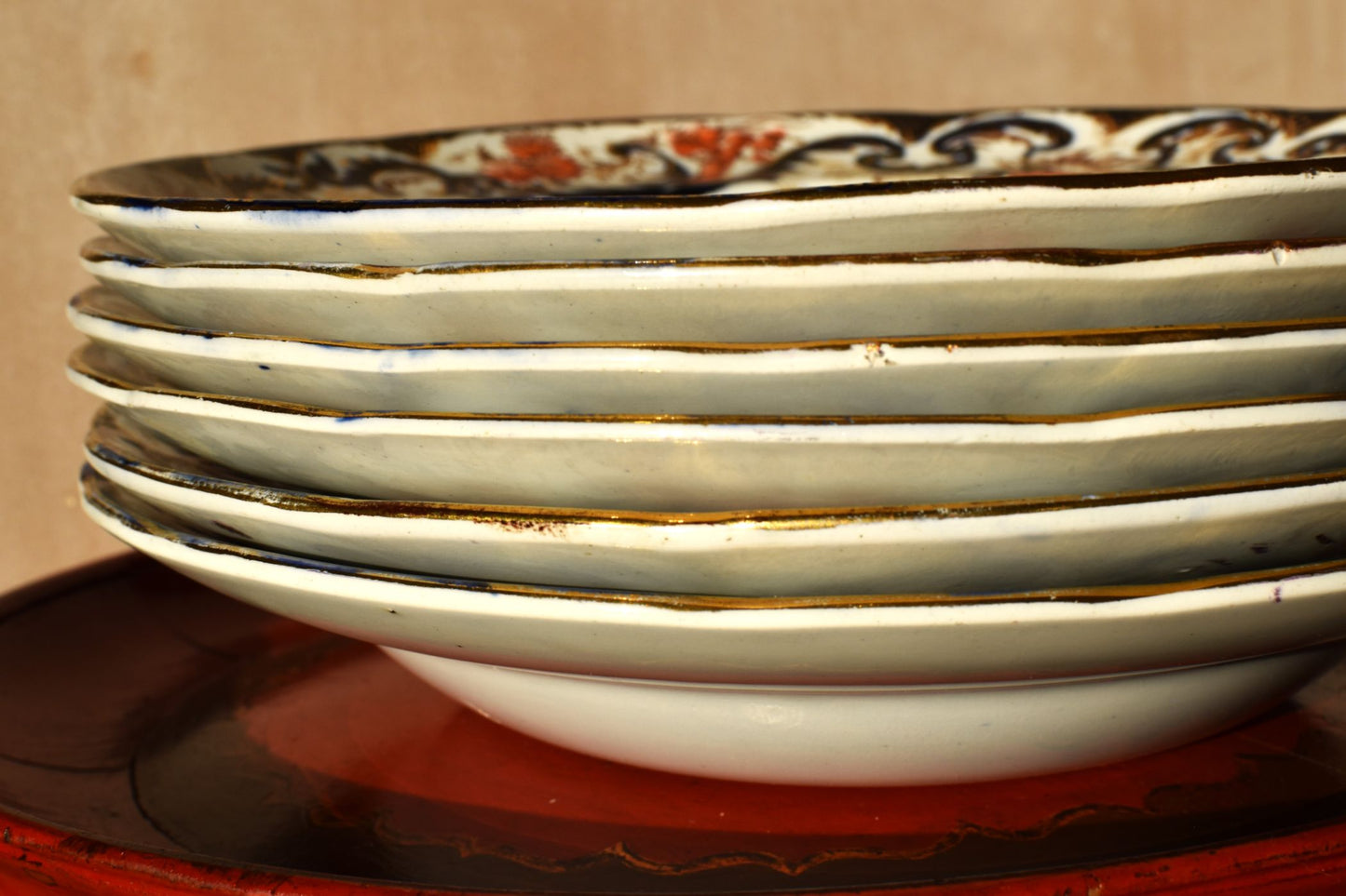 Stack of ceramic plates with decorative rim on a wooden surface