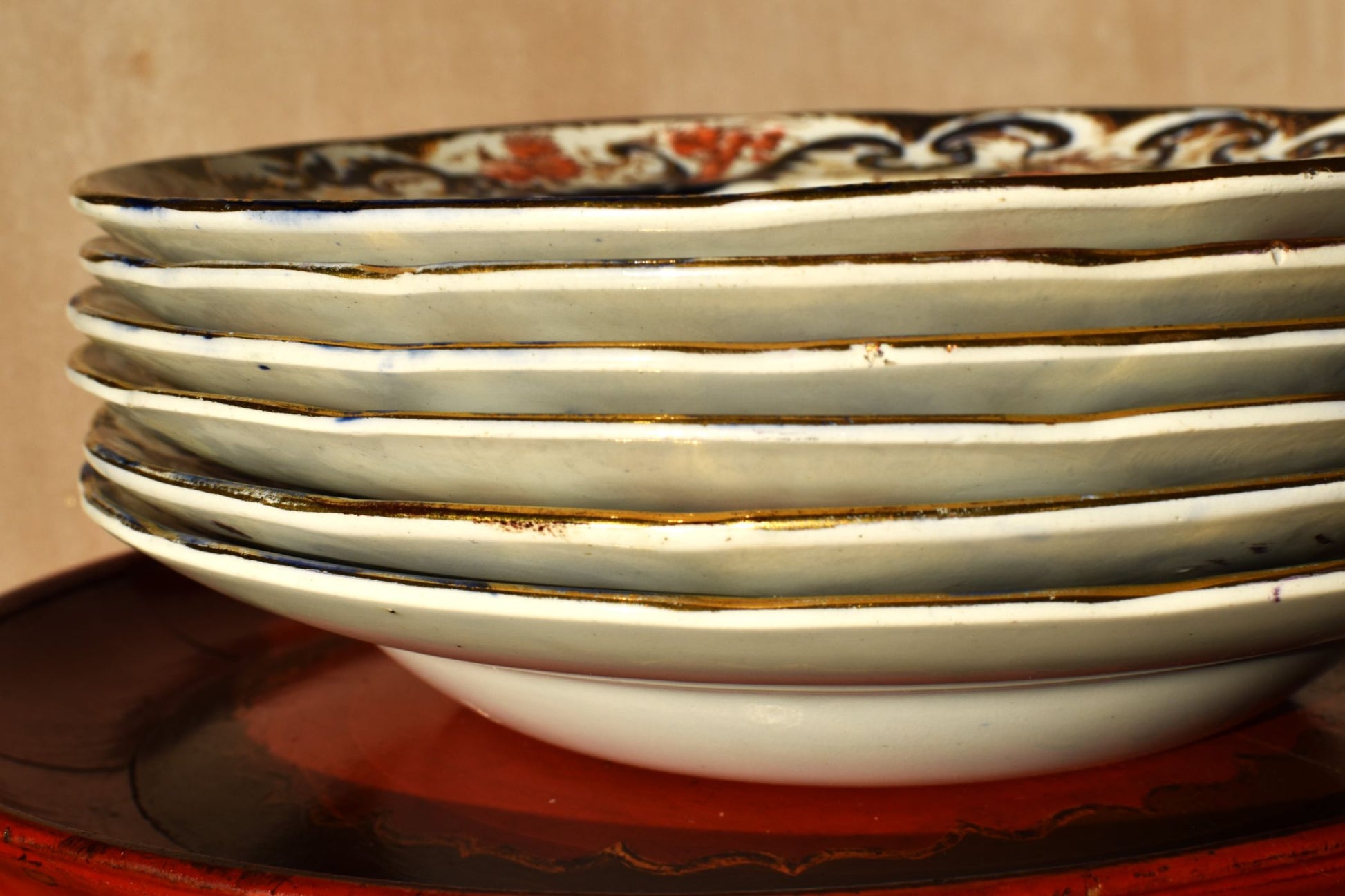 Stack of ceramic plates with decorative rim on a wooden surface