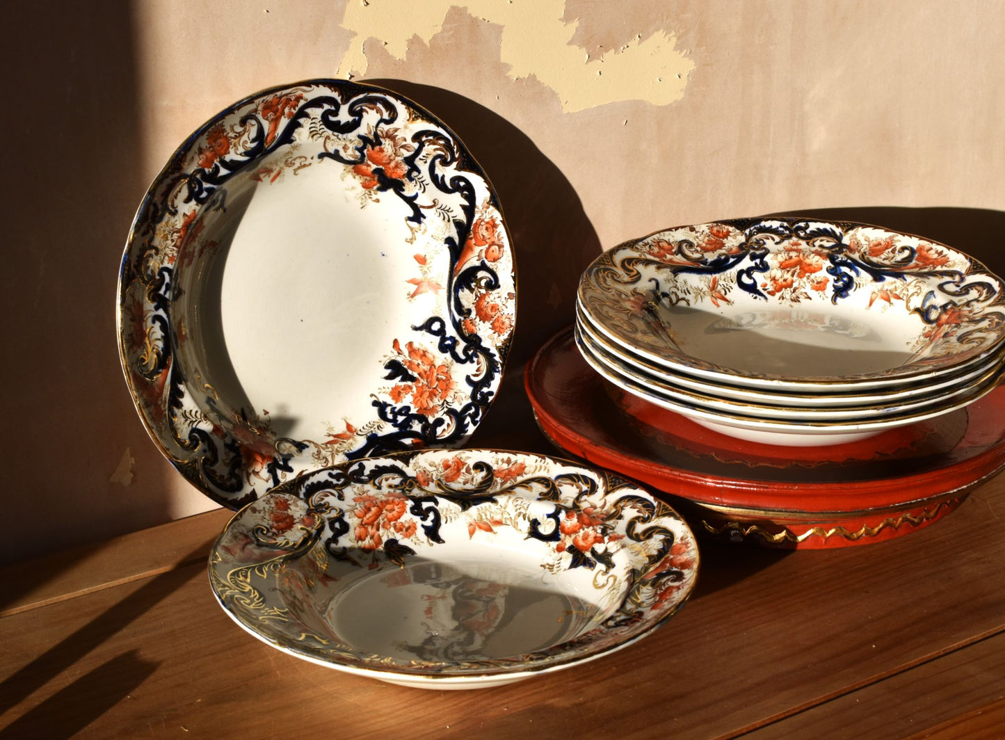 Set of decorative ceramic plates with floral patterns on a wooden surface.
