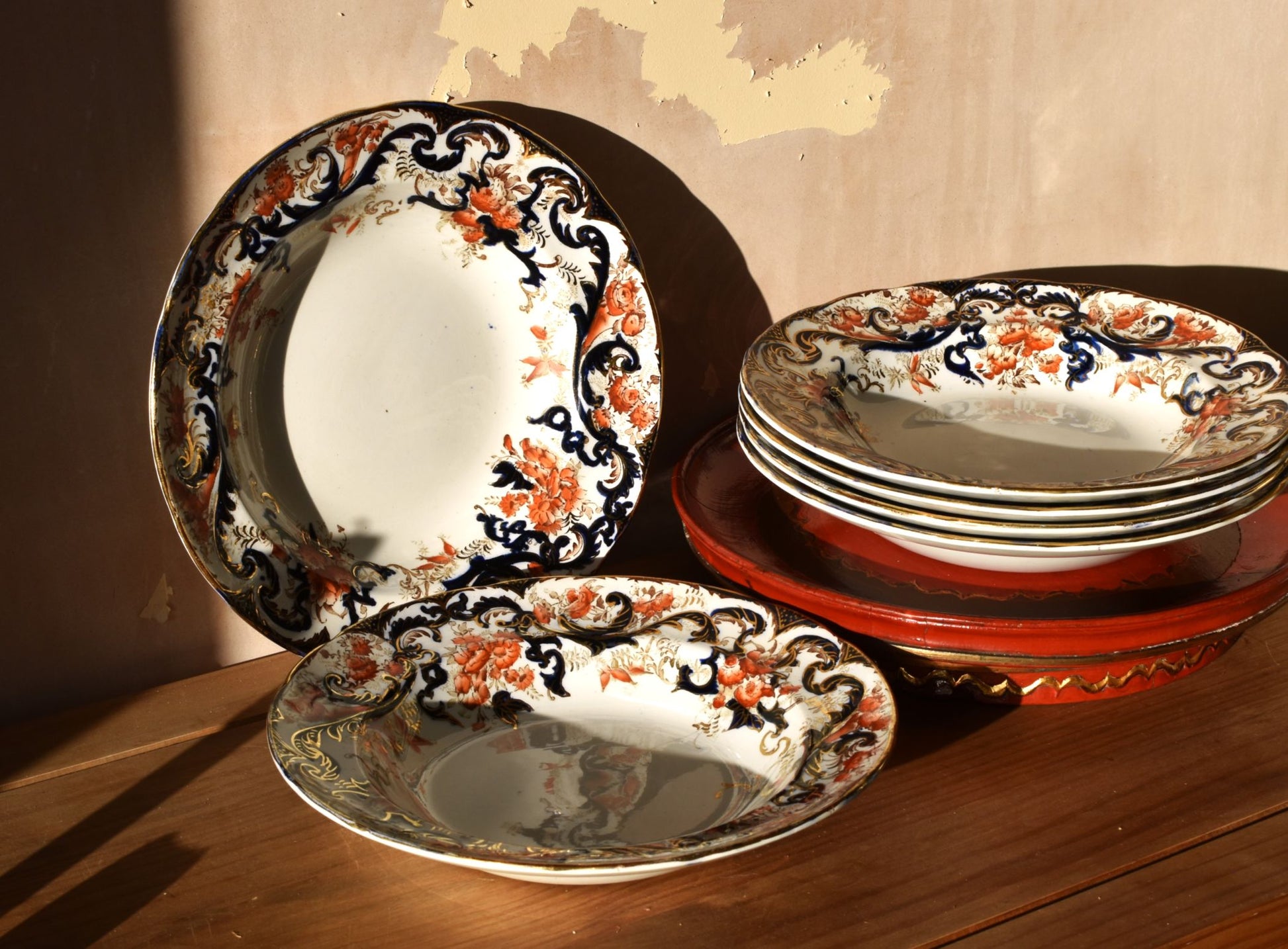 Set of decorative ceramic plates with floral patterns on a wooden surface.