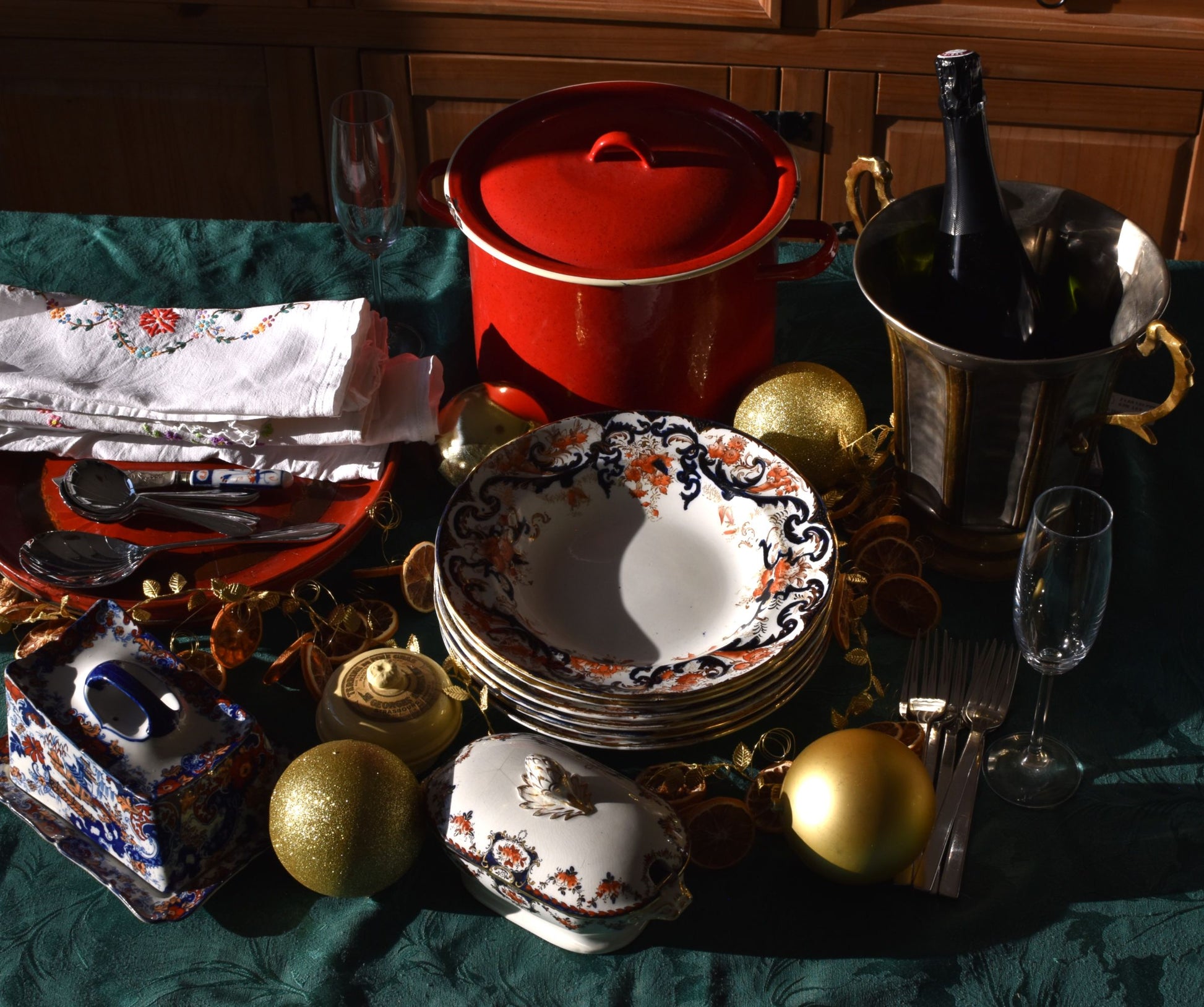 a table is set with plates,dishes, a big red pot and christmas baubles