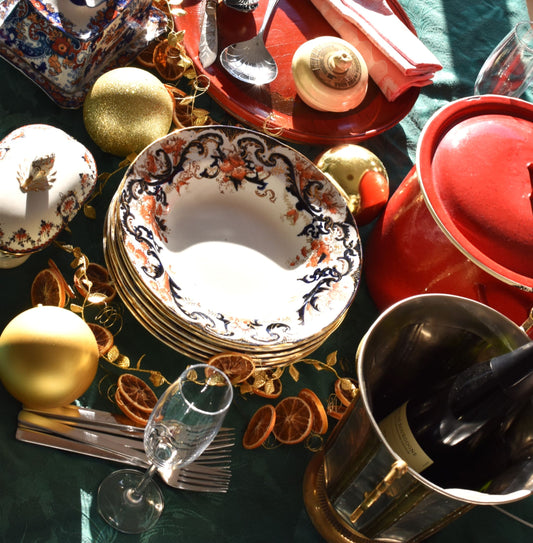 Decorative table setting with plates, glasses, and ornaments on a green surface.