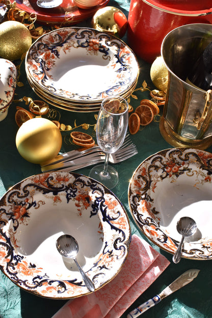 Decorative table setting with ornate plates, glasses, and cutlery on a green tablecloth.
