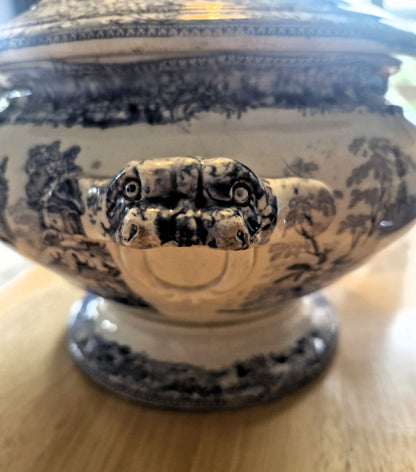 Decorative urn with intricate design on a wooden surface. Handle looks like a snake's open mouth