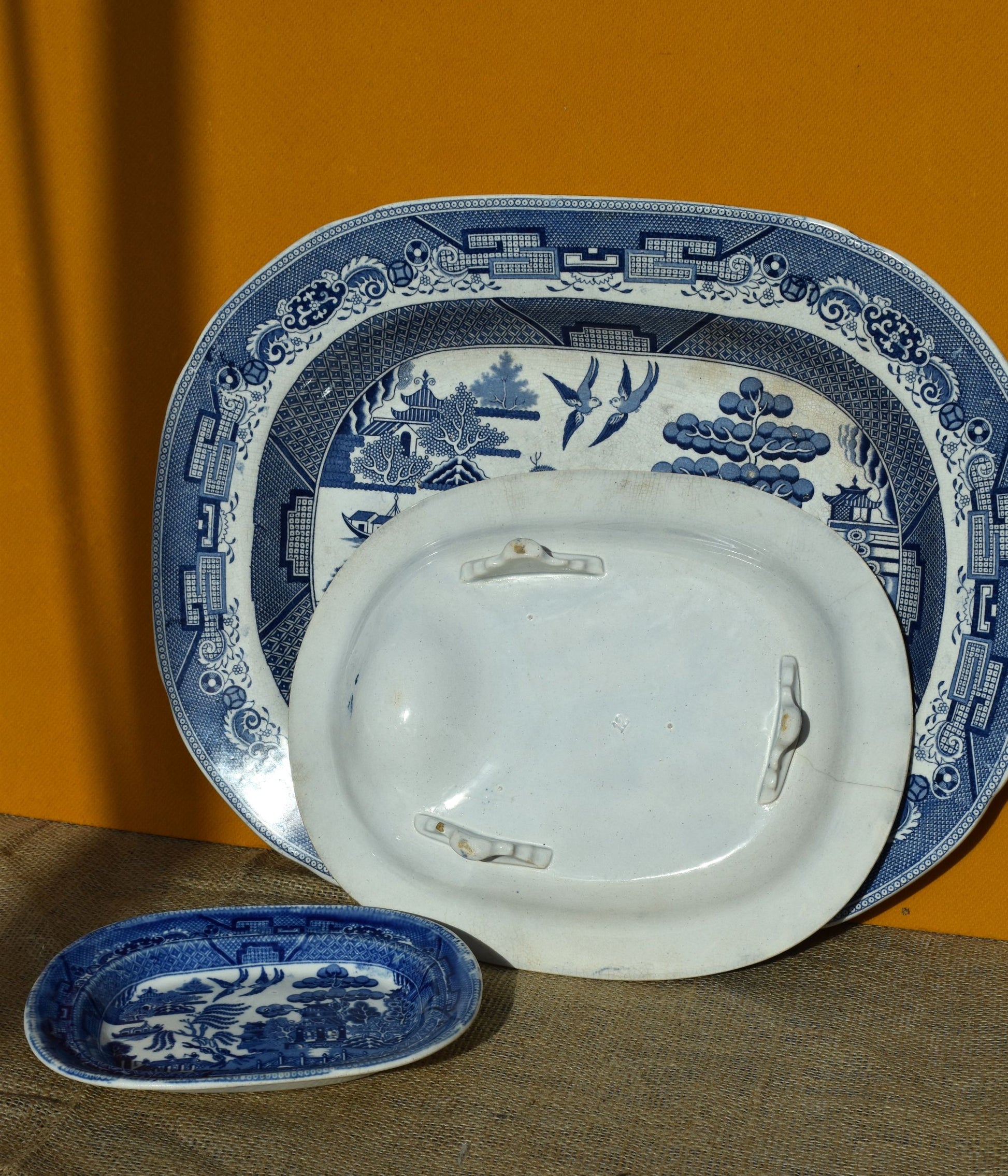 Set of blue and white ceramic plates on a brown surface with an orange background