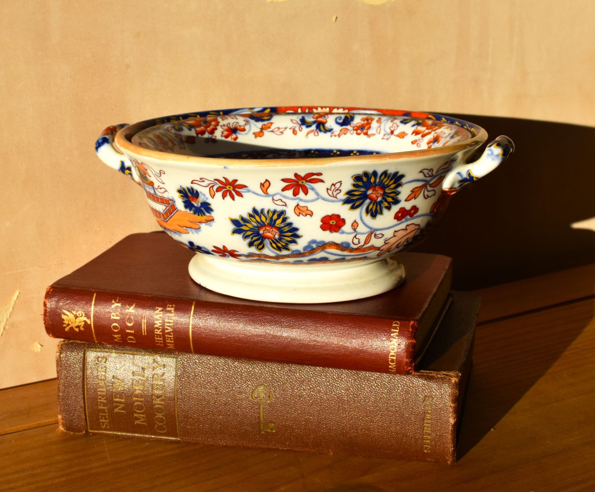 Decorative ceramic bowl with floral patterns on top of two old books.