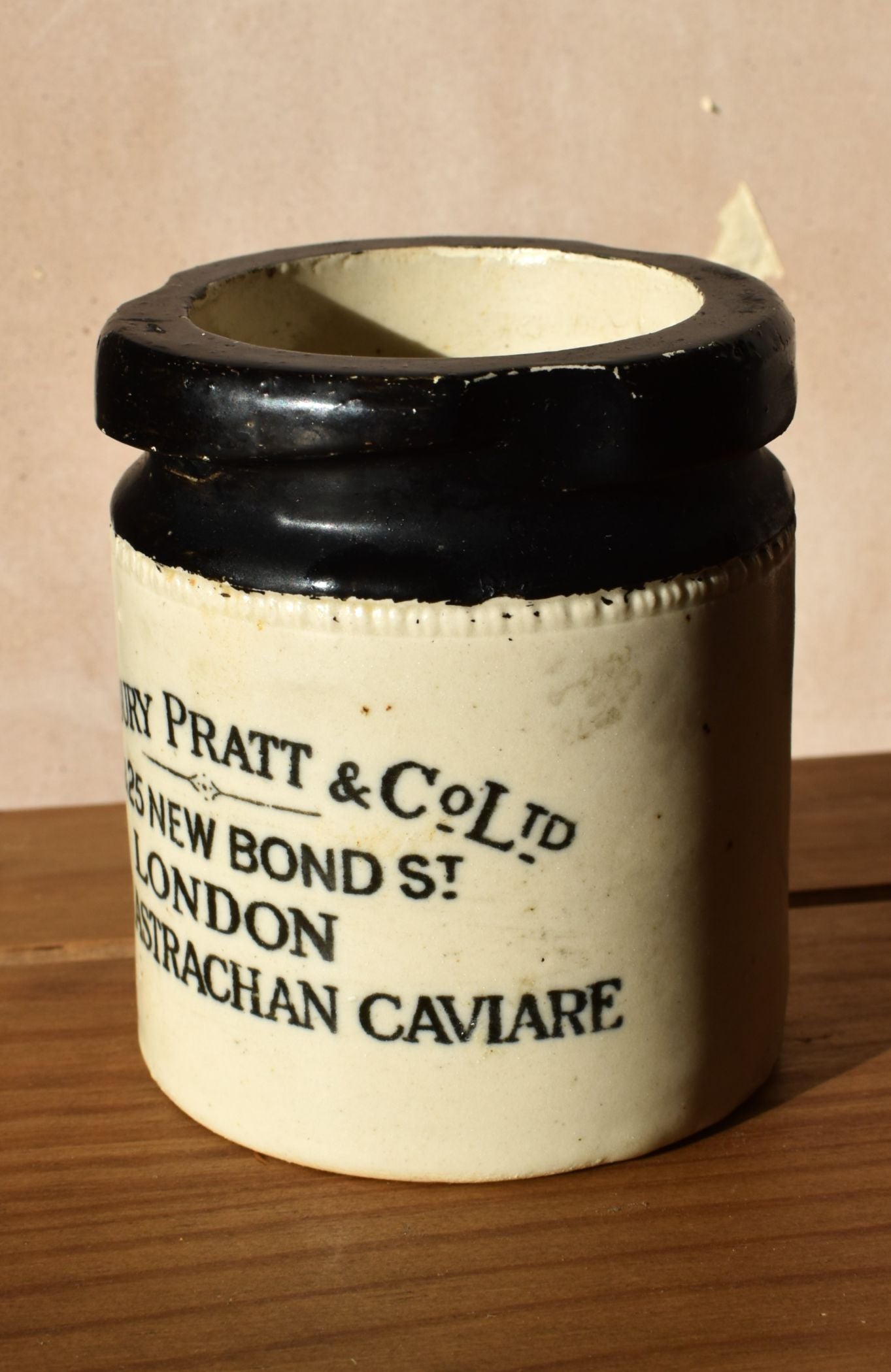 Vintage caviar jar with 'Pratt & Co.' branding on a wooden surface.