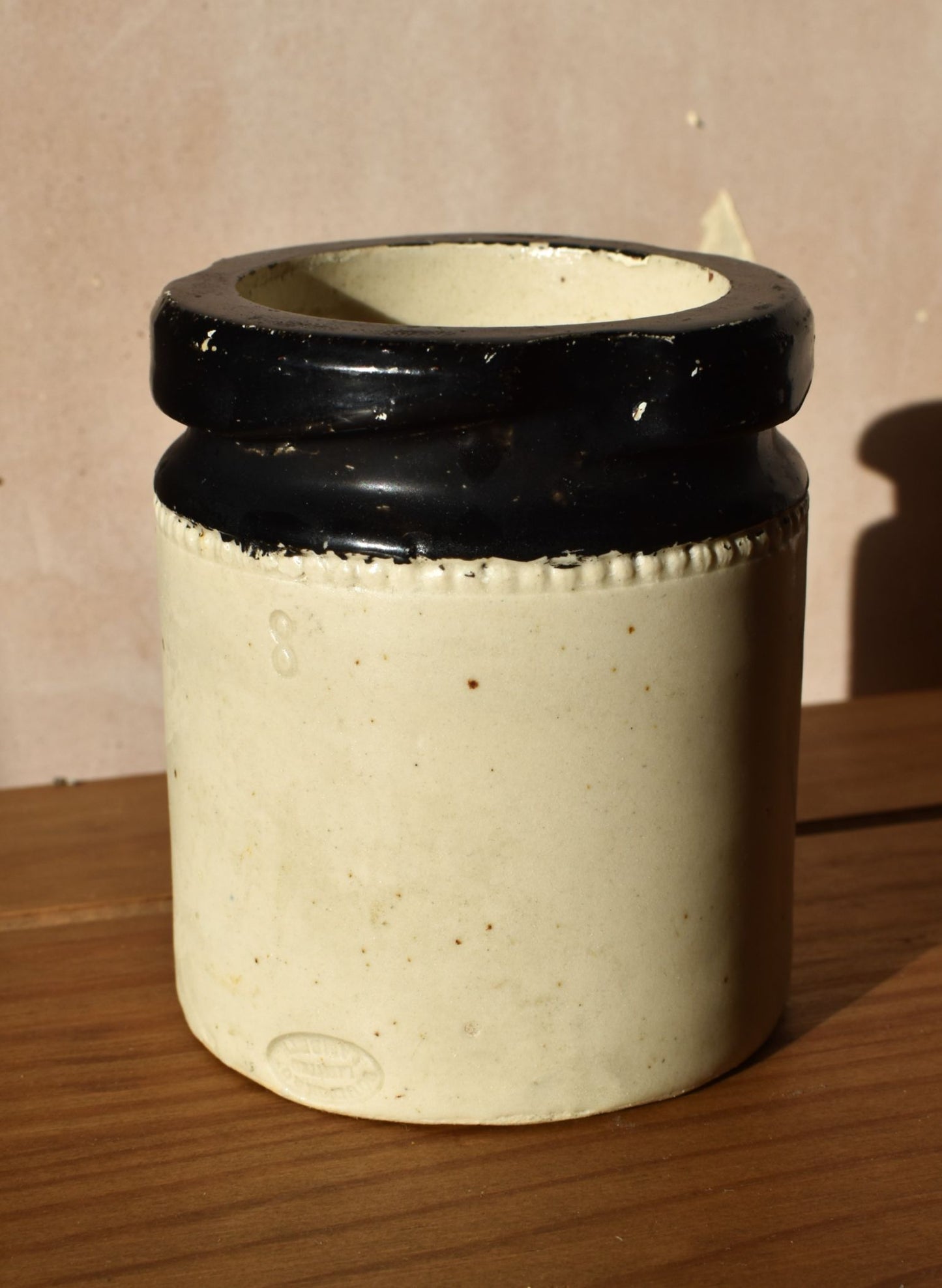 Cylindrical ceramic container with black ribbed top on a wooden surface