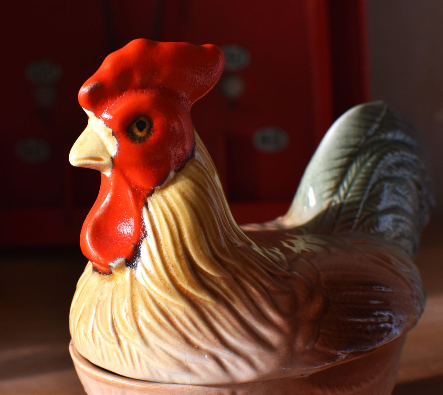 a close up of the dish shows the head painted red and the body of the rooster painted brown and green