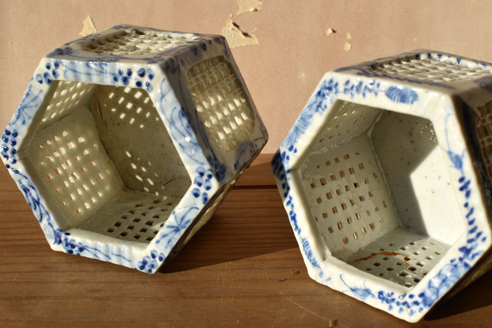 Two hexagonal ceramic planters with blue floral patterns on a wooden surface.