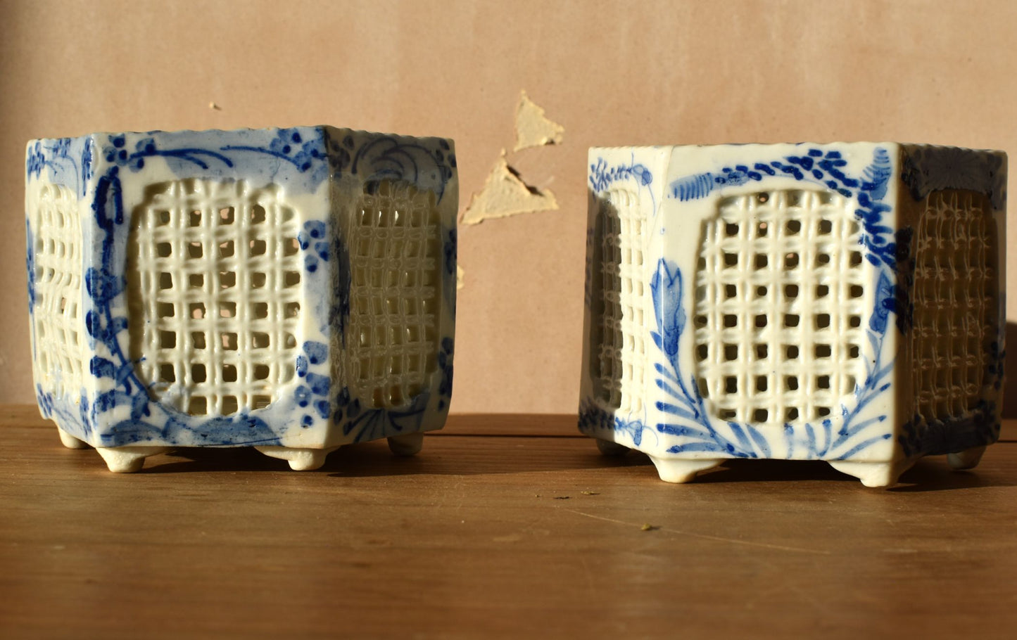 Two ceramic hexagonal containers with blue and white patterns on a wooden surface.
