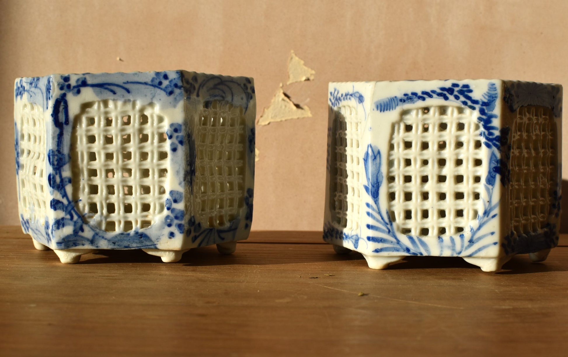 Two ceramic hexagonal containers with blue and white patterns on a wooden surface.