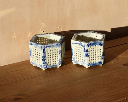 Two hexagonal ceramic pots with blue and white patterns on a wooden surface.