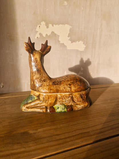 Decorative deer figurine on a wooden surface with a textured wall background