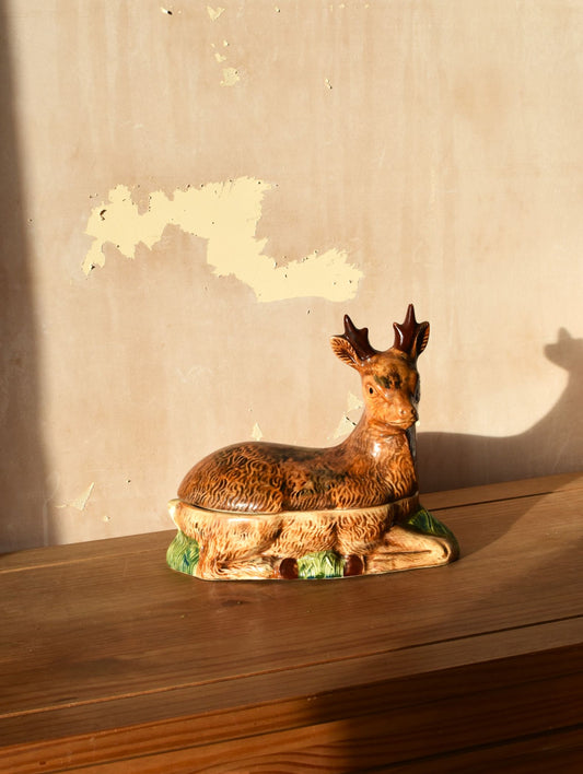 Decorative deer figurine on a wooden surface with a textured wall background