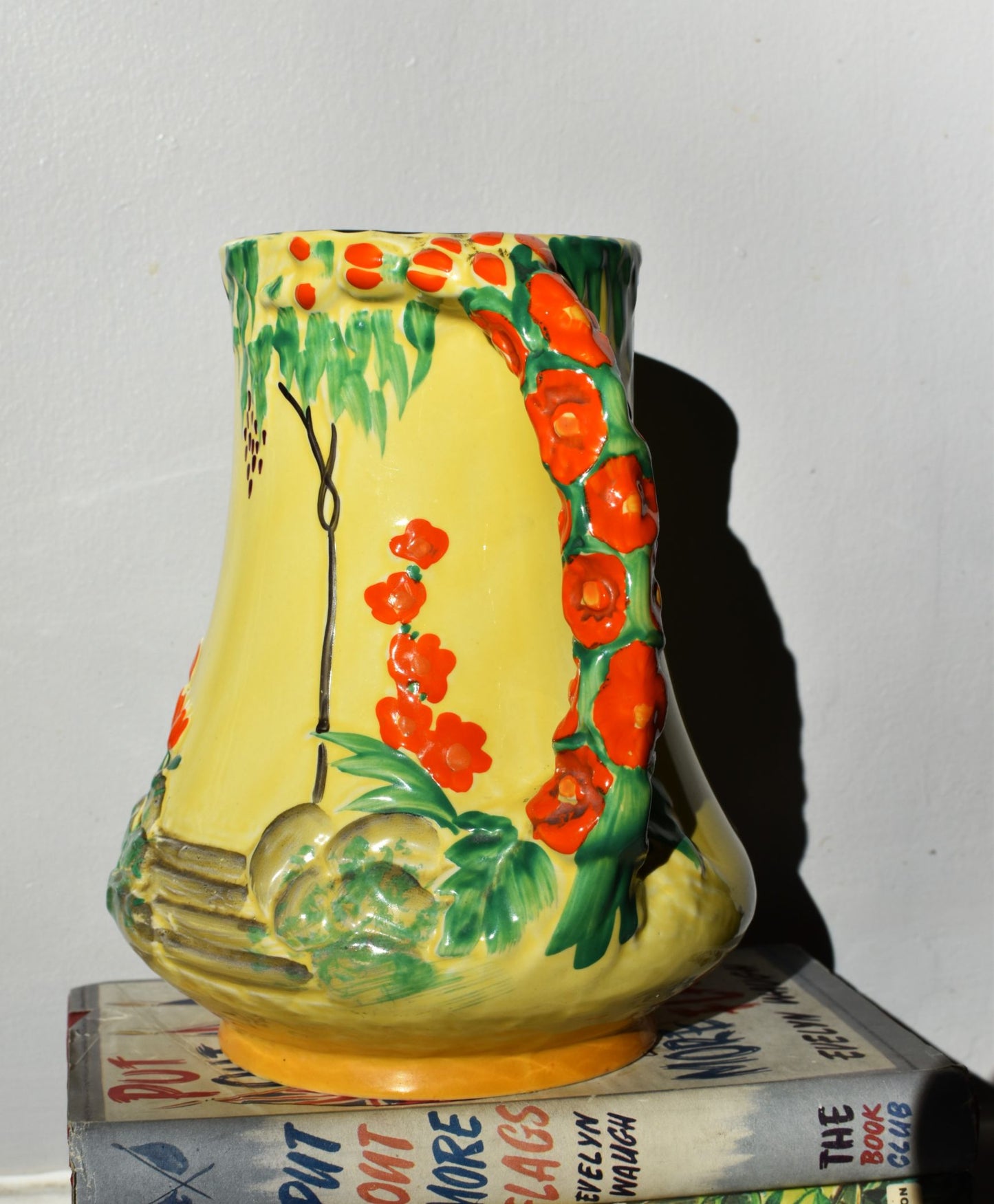 Decorative vase with floral design on a stack of books against a white background