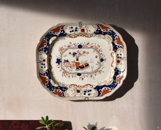cream, blue and red japanese floral plate hanging on a pink wall