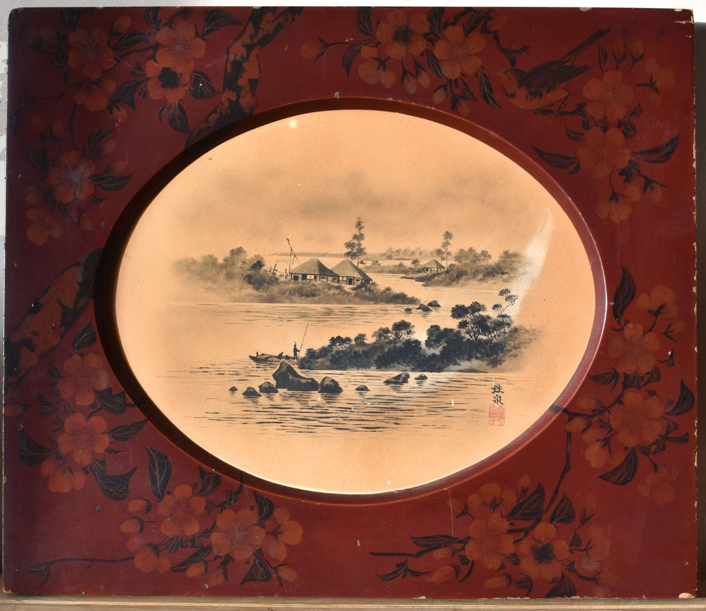 Decorative artwork with a circular landscape scene inside a red frame with floral designs.