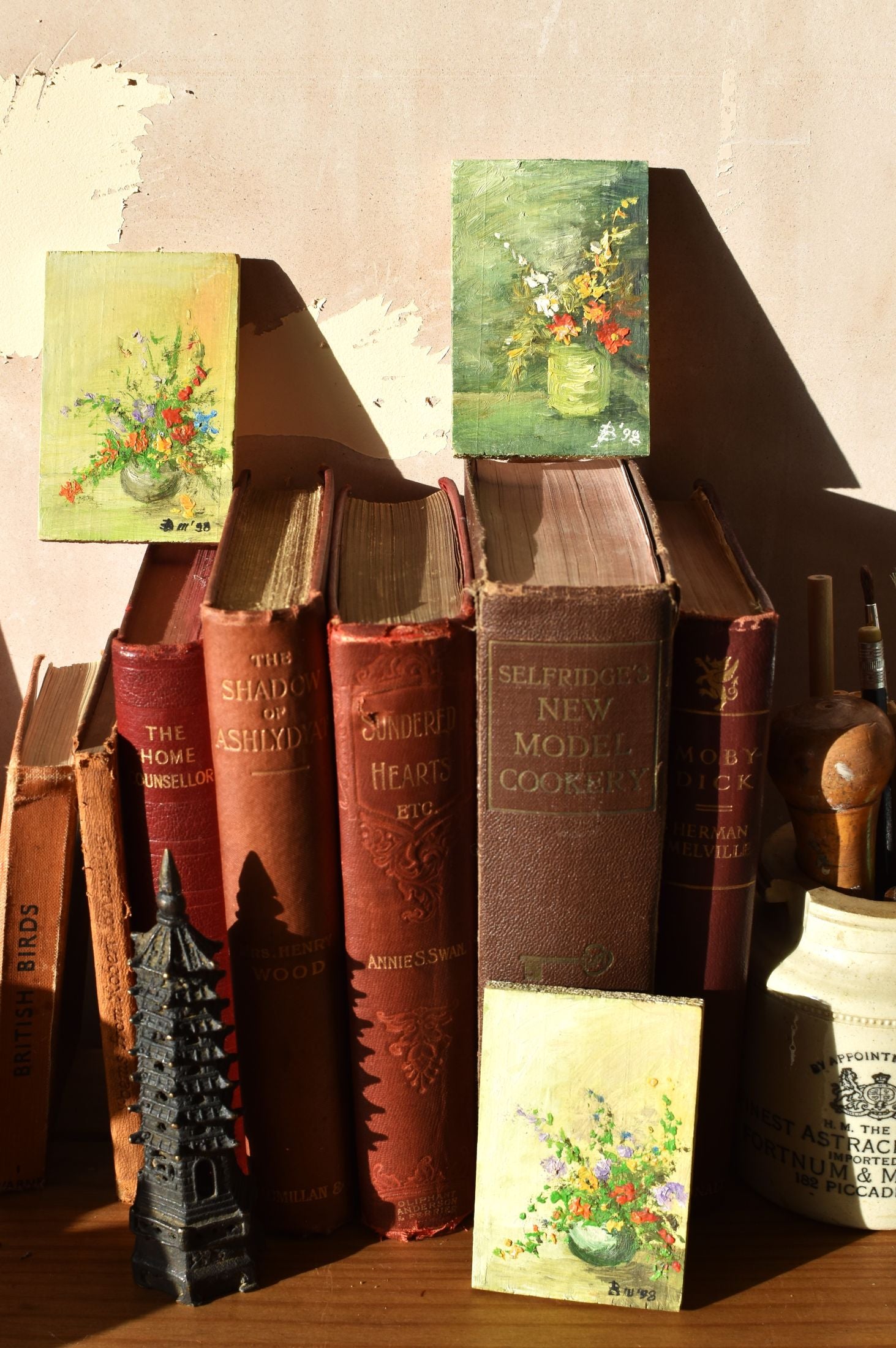 Stack of vintage books with decorative covers on a wooden surface.