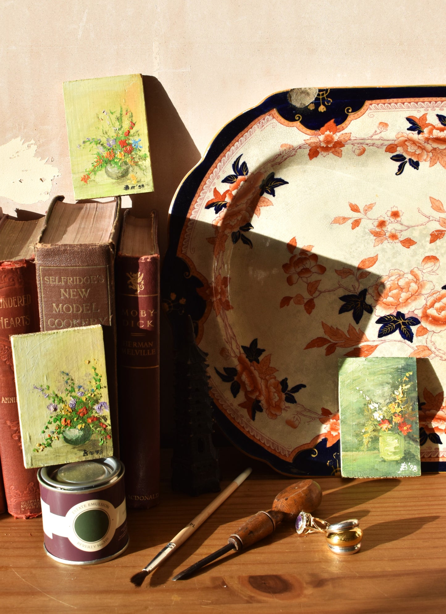 Decorative items including books, a can, a fan, and a decorative plate on a wooden surface.