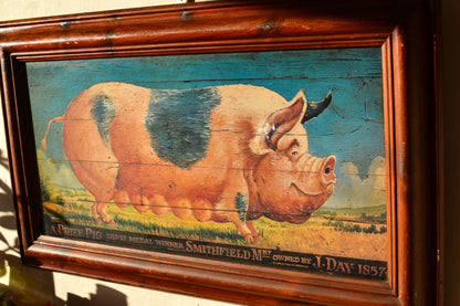 a large painting of a pig in Victorian style with a dark wooden frame hangs on a pink wall