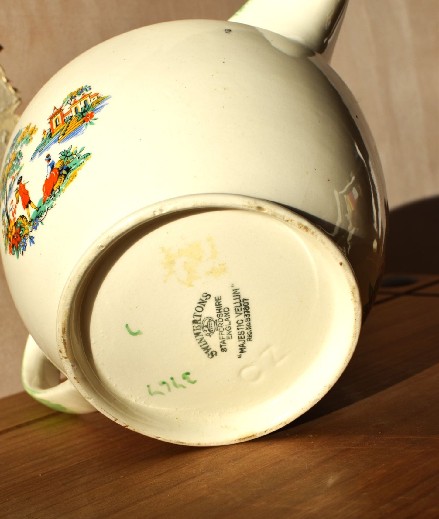 Vintage ceramic teapot with colorful designs on a wooden surface